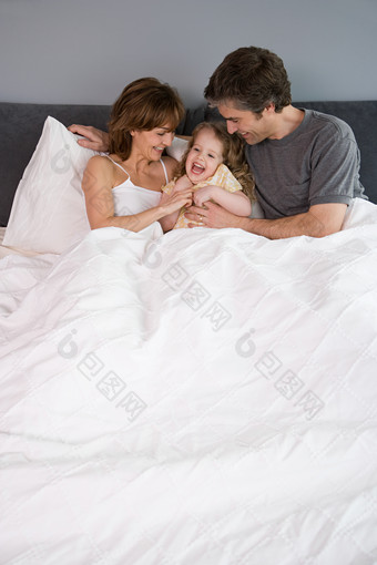 暗色调床上的一家人摄影图