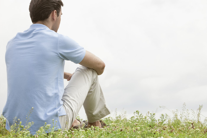 清新草地上坐着的男人摄影图