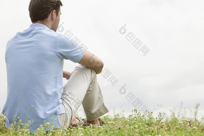 清新草地上坐着的男人摄影图
