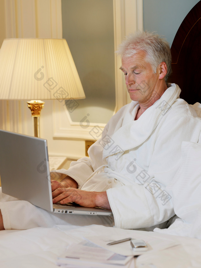 穿浴袍使用电脑的老年人