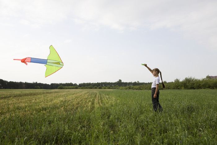 草坪上放风筝的小女孩