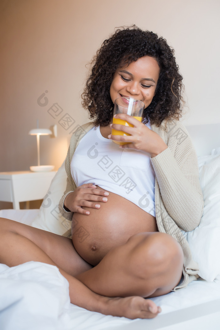 黑人孕妇抚摸孕肚喝果汁