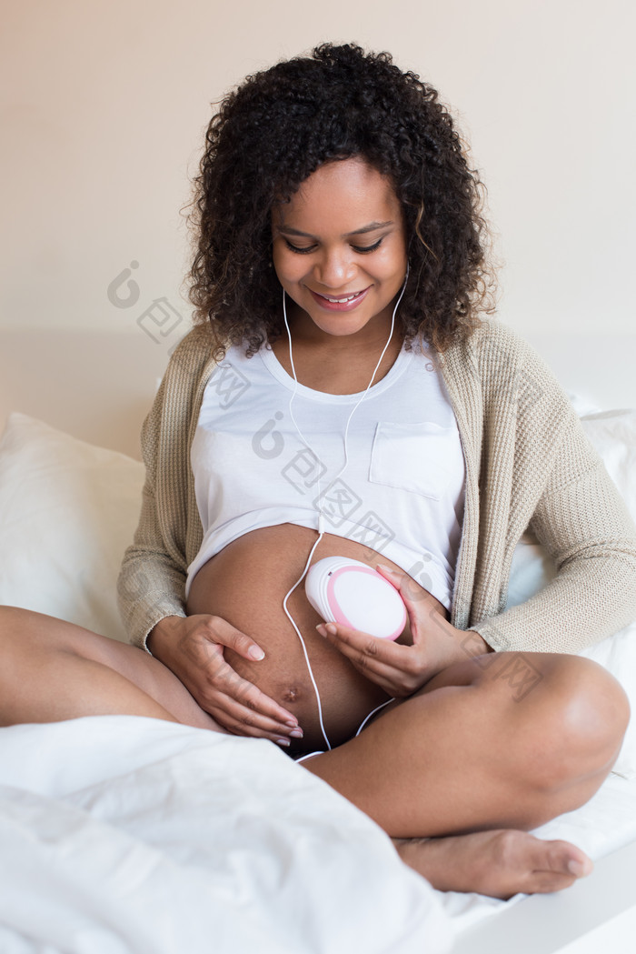 孕妇坐在床上听胎儿心跳