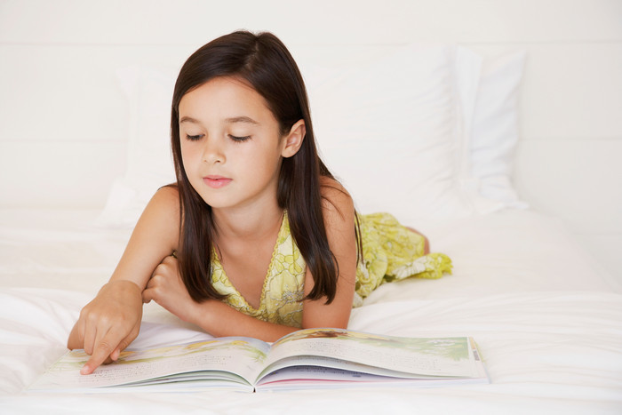 女孩趴在床上阅读书籍