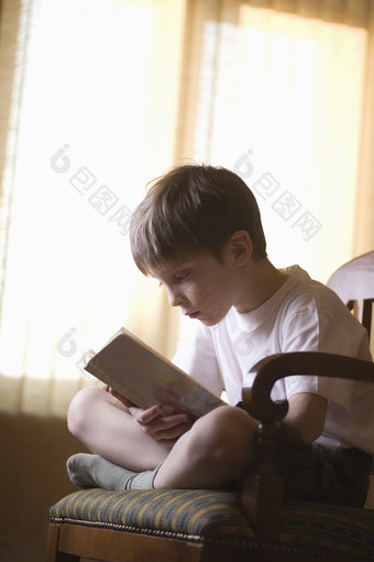 男孩<strong>坐在椅子上</strong>看书