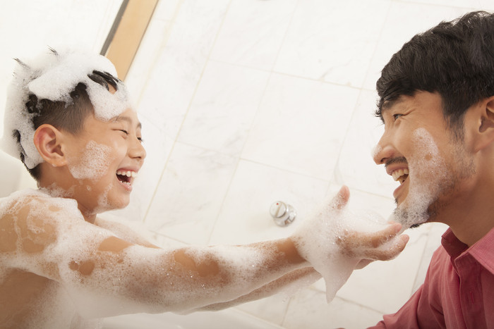 小男孩泡澡浴缸泡泡洗澡爸爸家人微笑摄影图