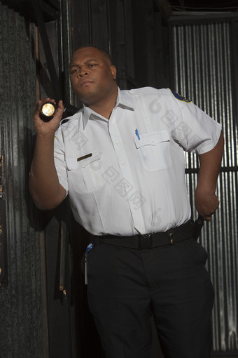 暗色调拿电筒的男警察摄影图