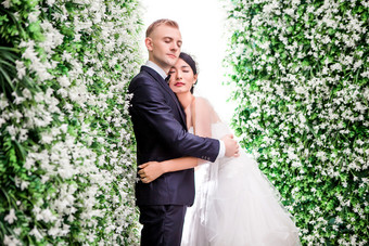 白色花墙边拍婚纱照的夫妻