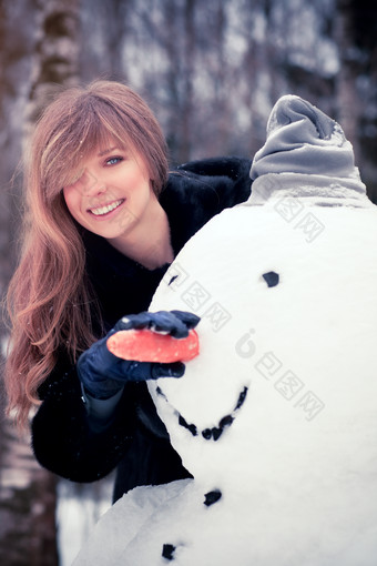 深色调堆雪人的女孩摄影图