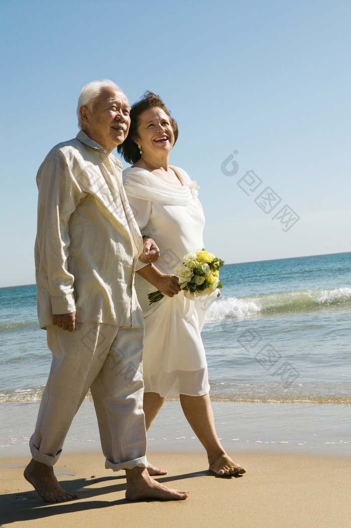蓝色调海边散步的老夫妻摄影图