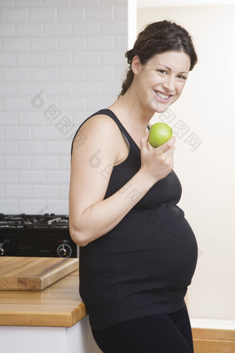 深色调吃水果的孕妇摄影图