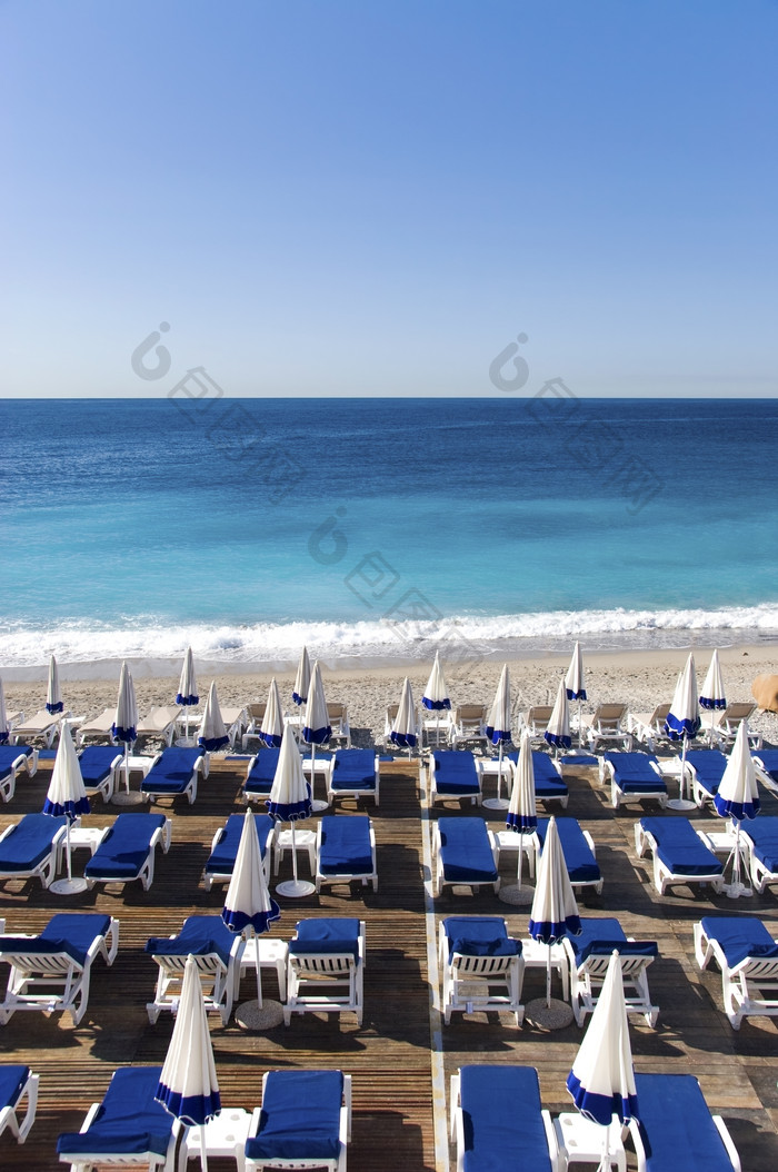 蓝色沙滩上的遮阳伞摄影图