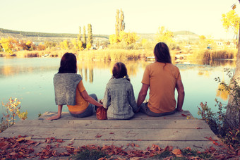 坐在湖水边一家人背影
