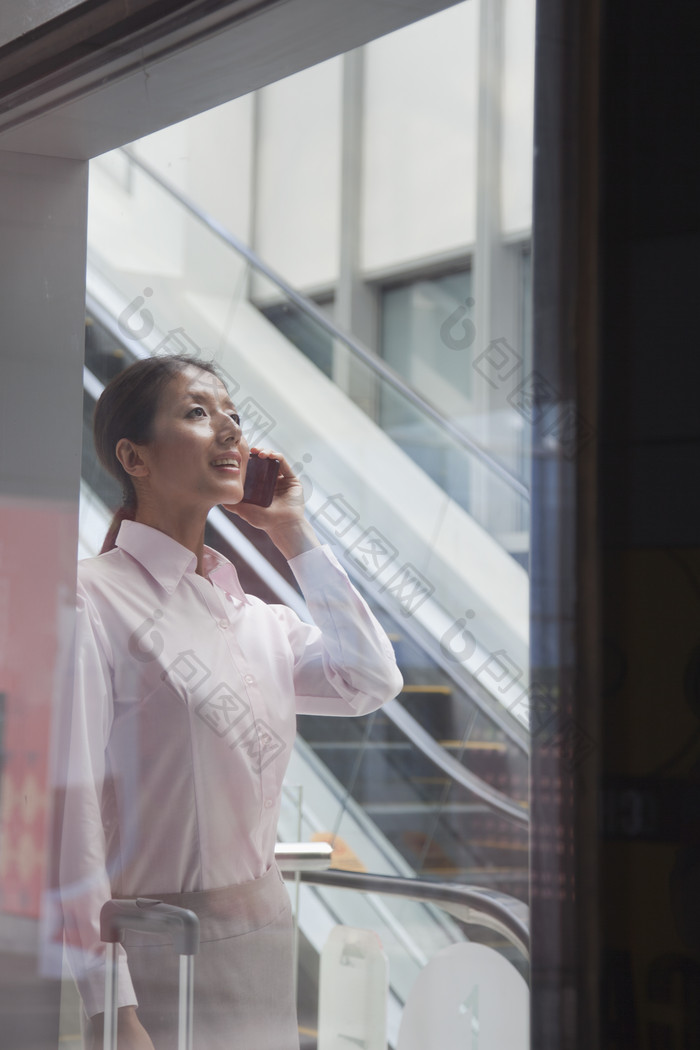 女人成熟的衬衫接电话商业业务行李箱出差