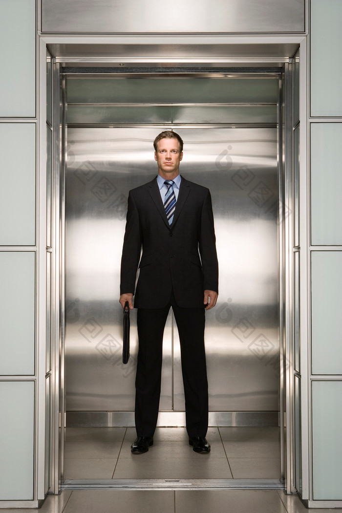 深色调电梯中的商人摄影图