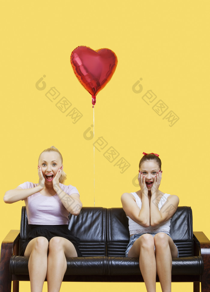 两个女孩开心捂脸坐在沙发