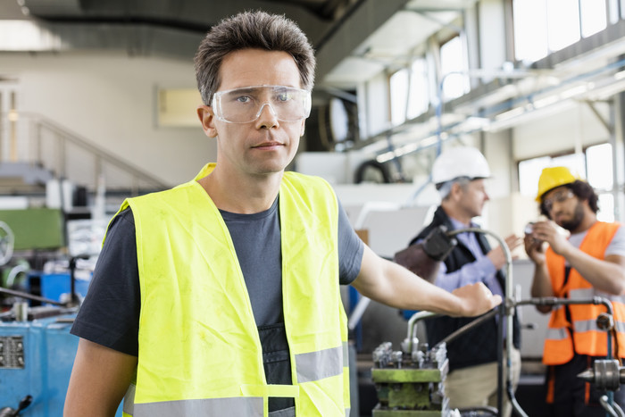工人戴着防护眼镜站在工厂