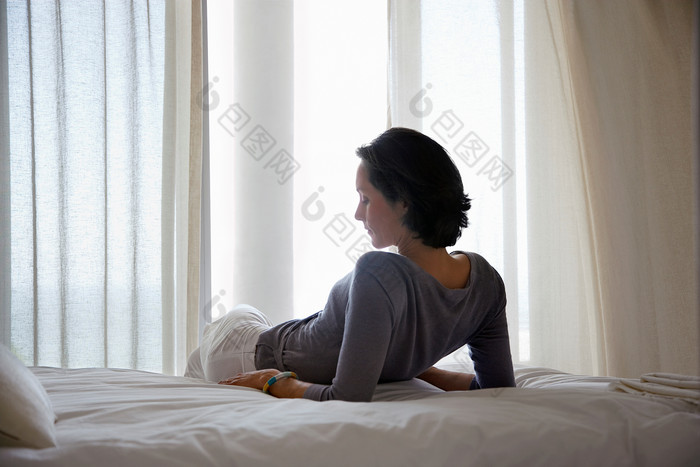 暗色调床上躺着的女人摄影图