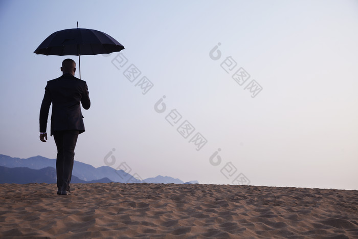 沙漠商务男士打伞背影