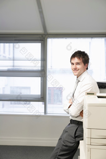 打印机旁边坐着微笑的男子