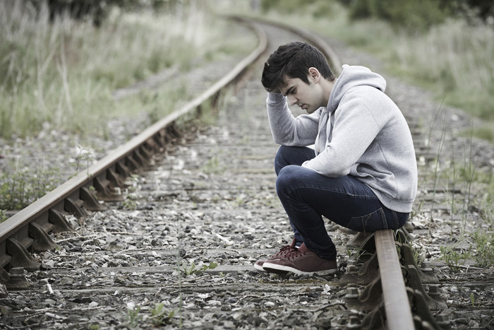 坐在铁轨上的抑郁男孩