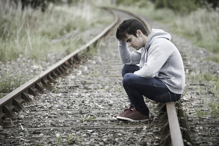 坐在铁轨上的抑郁男孩