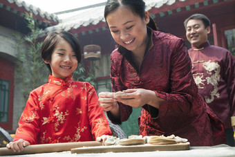 在院子里包饺子的一家人