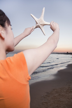 海滩边手持海星的女孩