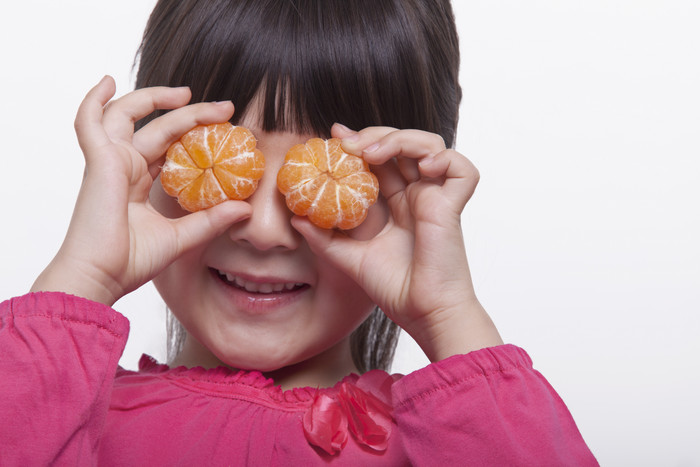 可爱女孩拿橘子挡住眼睛