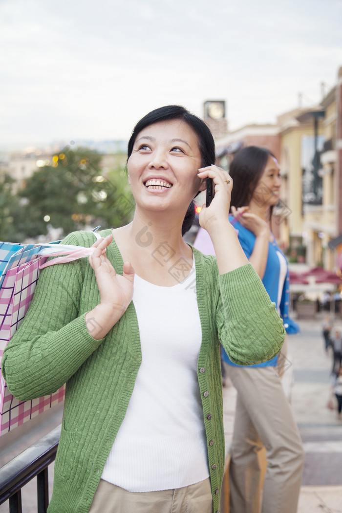 女人年轻的城市户外逛街购物袋开心的听电话