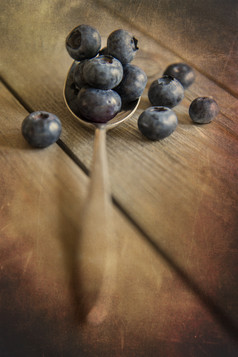 暗色调汤匙中的蓝莓摄影图