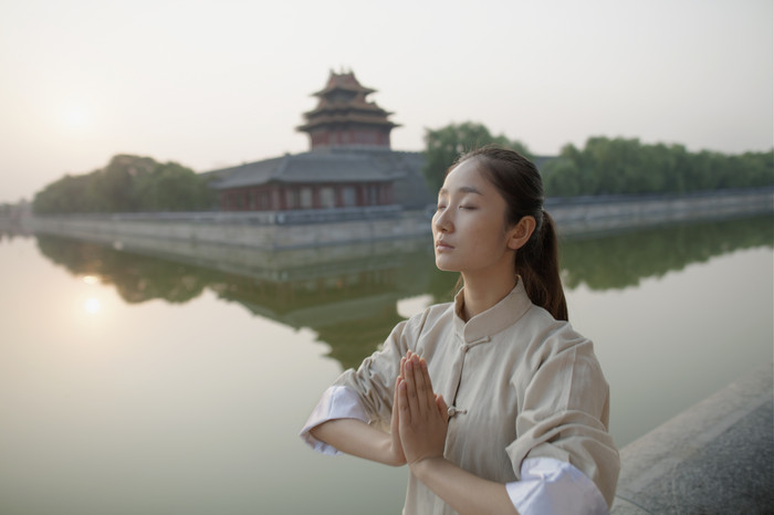 河边双手合十健身的女人