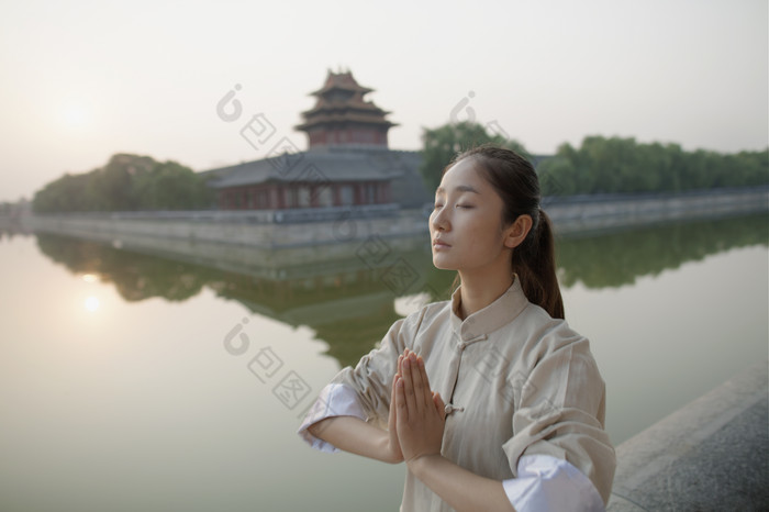 河边双手合十健身的女人
