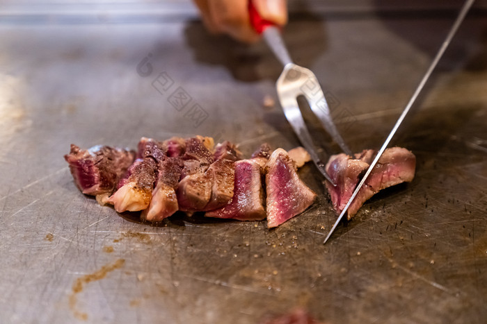 拿着小刀在石板上切割烤肉的人