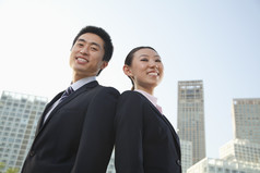 男人女人背靠背成熟的微笑城市户外业务工作