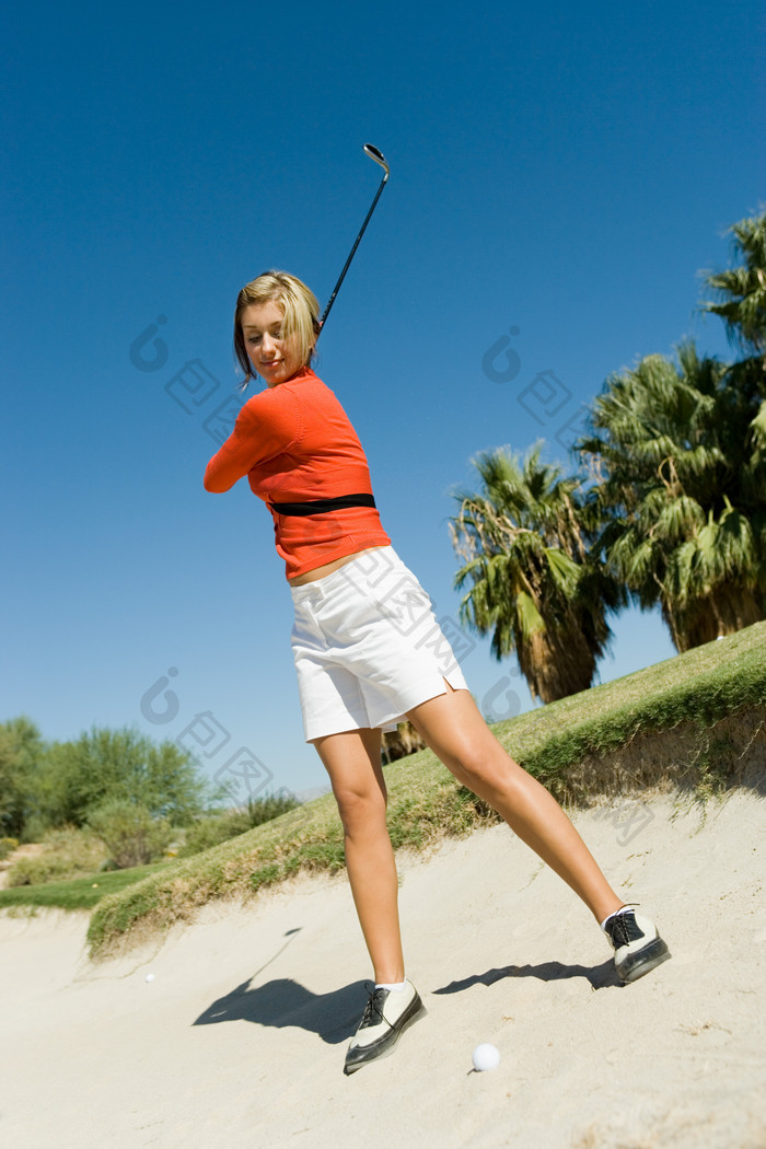 沙滩打高尔夫球的女人
