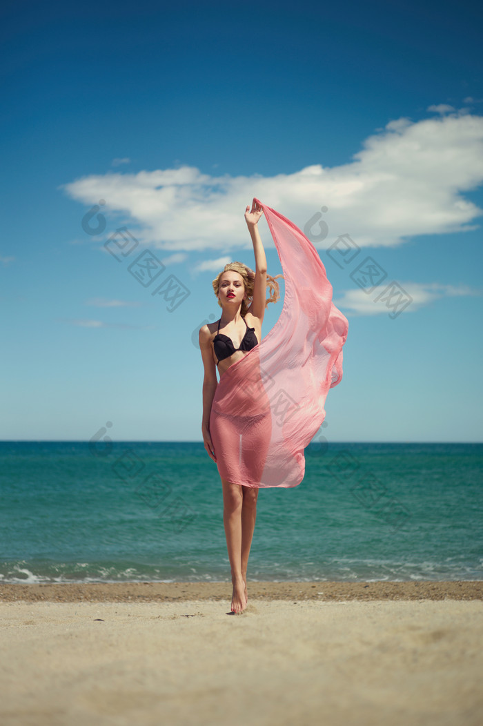 海滩上拿着纱巾的女人
