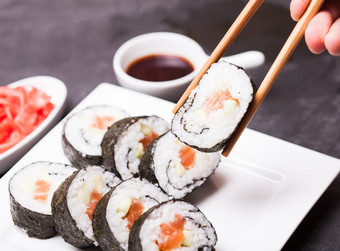 筷子夹起的寿司摄影图