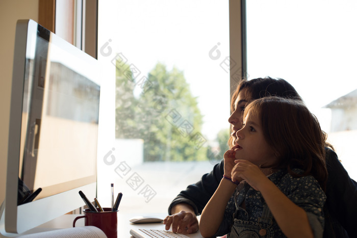 母亲和女孩坐在电脑前