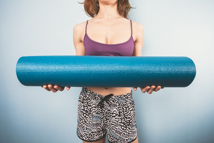 蓝色调拿瑜伽垫的女人摄影图