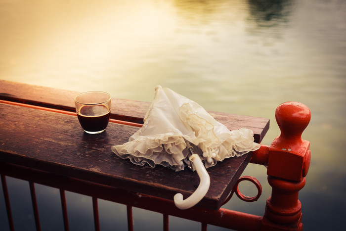 河边木桌上的雨伞和咖啡杯