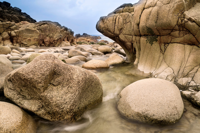 深色调海边的大石头摄影图