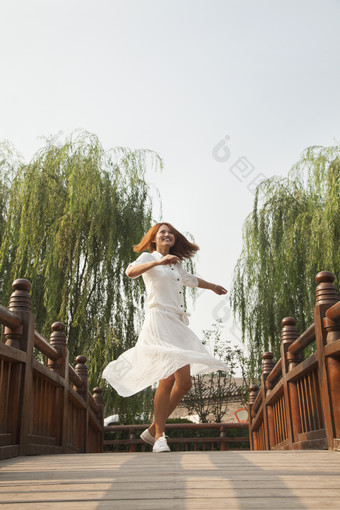 年轻的女人桥上欢快的跳跃青春的摄影图片