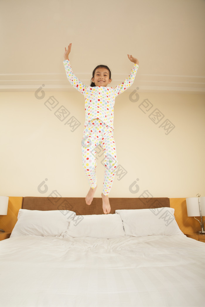 女儿小女孩穿着睡衣高兴跳起来床上摄影图片