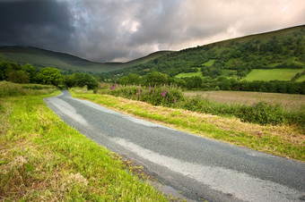 绿色调山下的公路摄影图