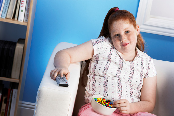 看电视吃糖果的肥胖女童