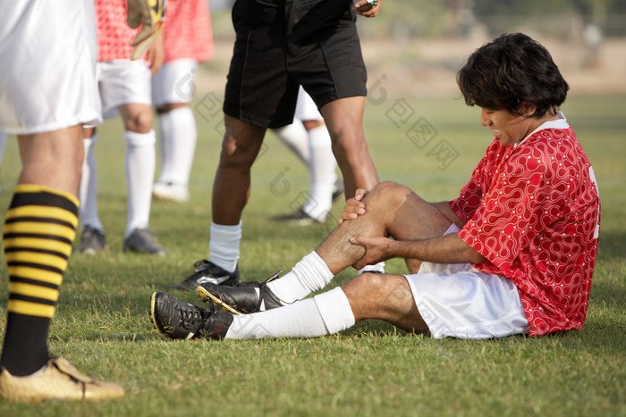暗色调踢足球受伤的孩子摄影图