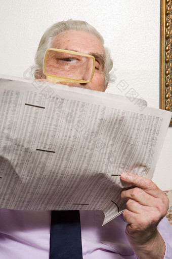 暗色调看报纸的老人摄影图