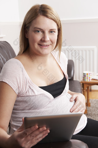 孕妇拿着平板电脑坐在沙发上