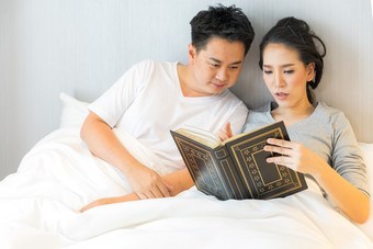 躺在床上阅读书籍的夫妻
